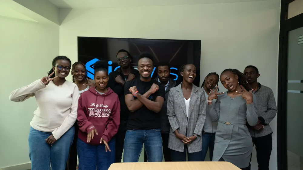 Once jóvenes sonríen frente a una pantalla con el logo de Signvrse; están de pie en una sala y posan con gestos alegres.